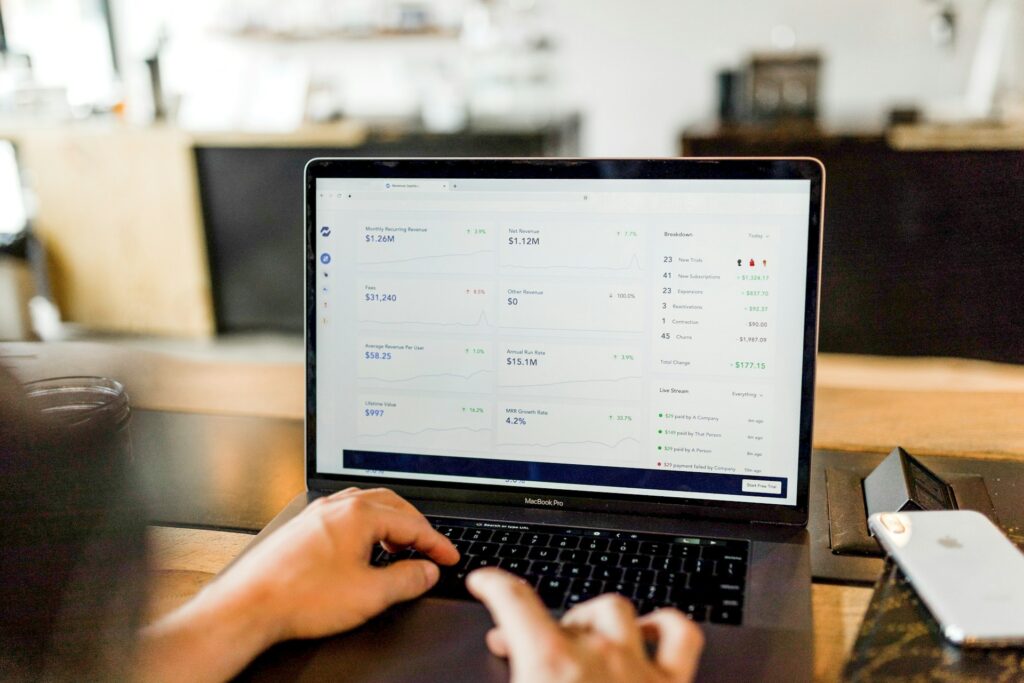 A person's hands using a MacBook Pro laptop looking at a screen of business statistics