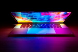 A half-closed laptop sitting on a flat surface, showing a vibrant, colourful screen