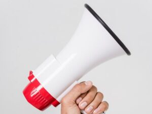 A close-up of a hand holding a large white and red megaphone